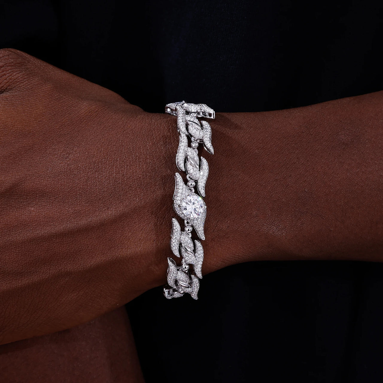 Silver bracelet with a diamond on a wrist against a dark background