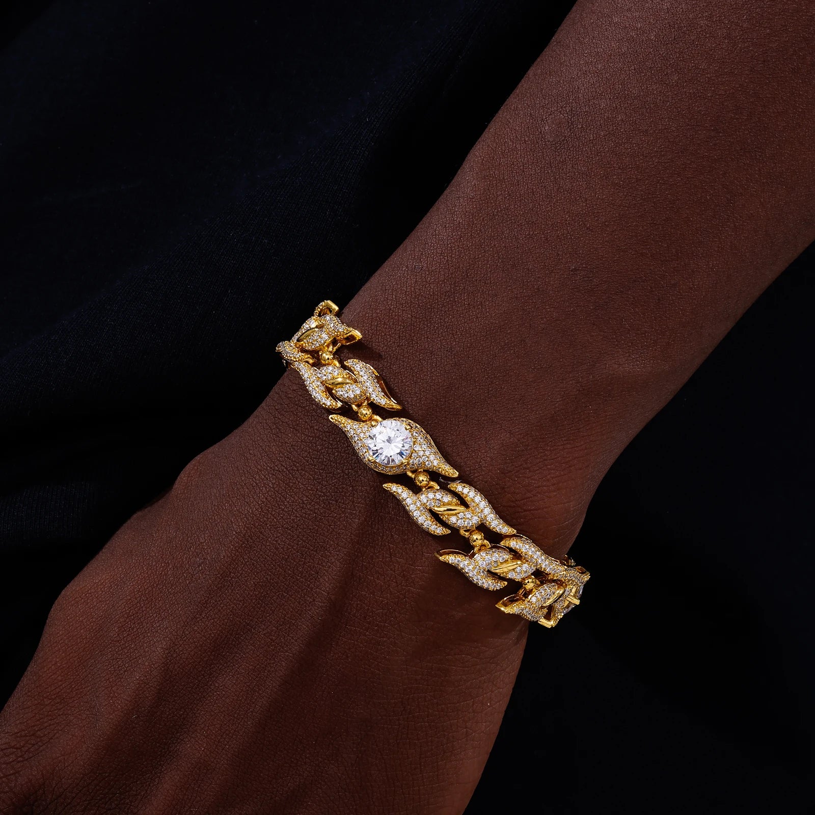 Gold bracelet with a diamond on a wrist against a dark background