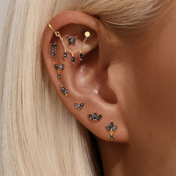 Close-up of an ear with multiple gold and black earrings.