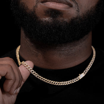 Close-up of a person wearing a gold chain necklace with a dark background