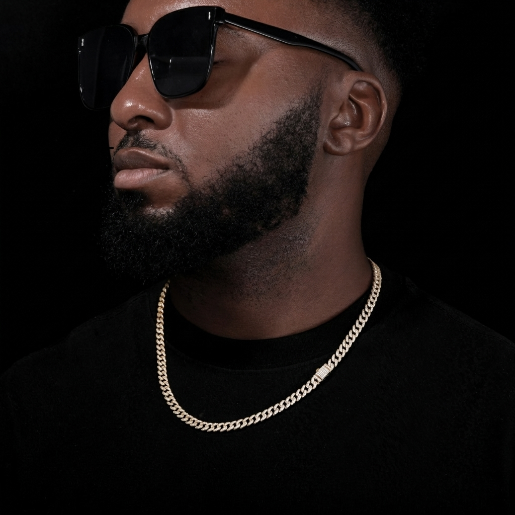 Man wearing sunglasses and a gold chain necklace against a black background