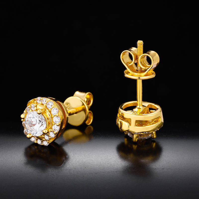 Gold earrings with clear gemstones on a reflective black surface