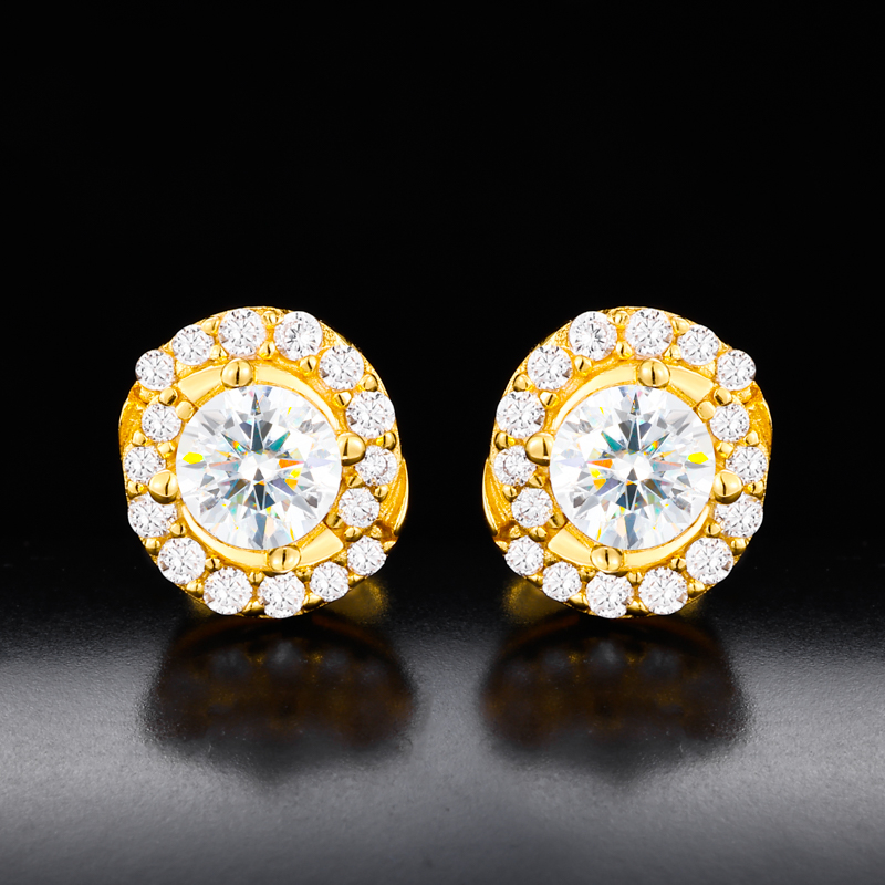 Gold earrings with clear gemstones on a reflective black surface