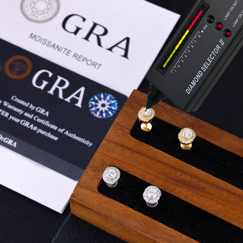 Diamond earrings on a wooden stand with a diamond selector tool and GRA report in the background.