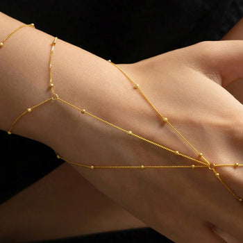 Gold bracelet on a wrist against a black background