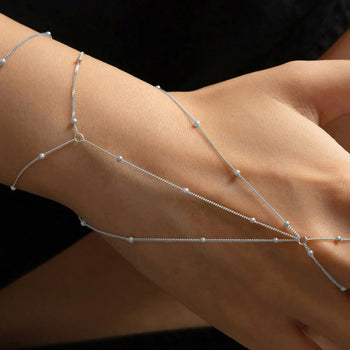 Silver arm chain on a person's arm against a black background