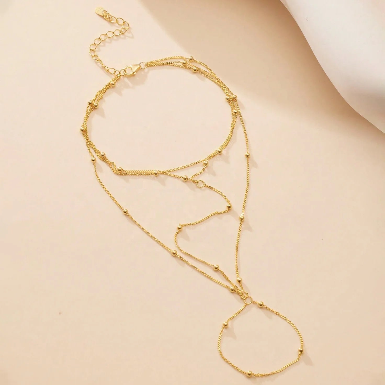 Gold layered necklace on a beige background