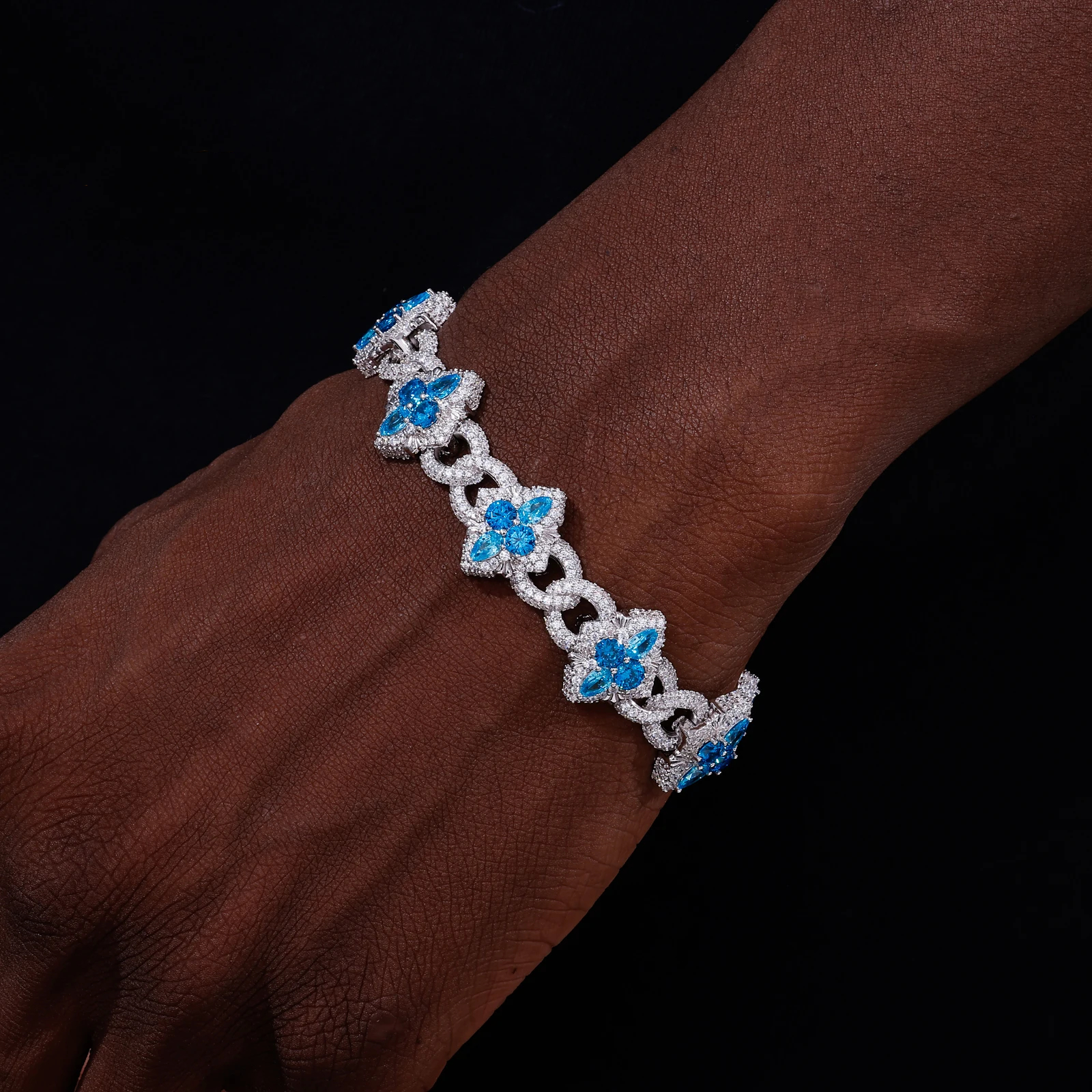 Bracelet with blue floral charms on a wrist against a dark background
