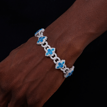 Bracelet with blue floral charms on a wrist against a dark background