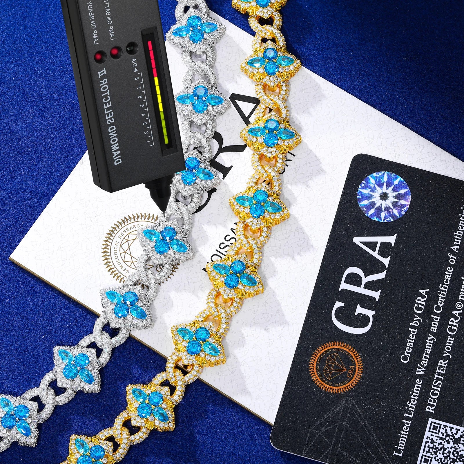 Decorative bracelet with blue stones on a white box, with a diamond detector and GRA card in the background.
