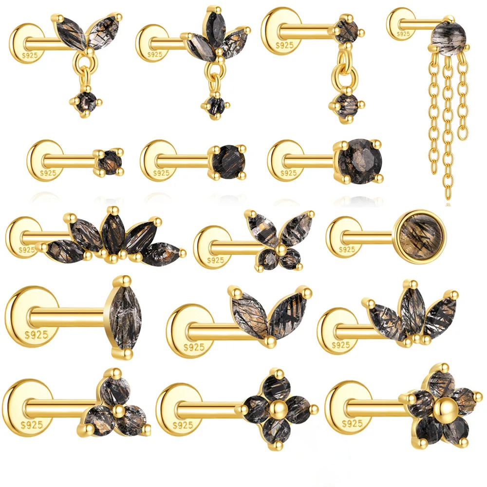 Close-up of an ear with multiple gold and black earrings.