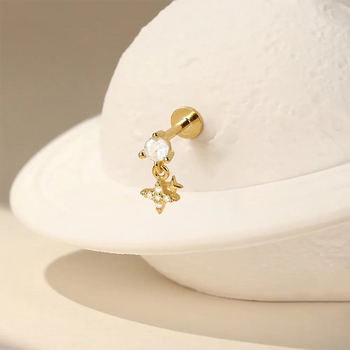 Gold earring with a small charm on a beige background