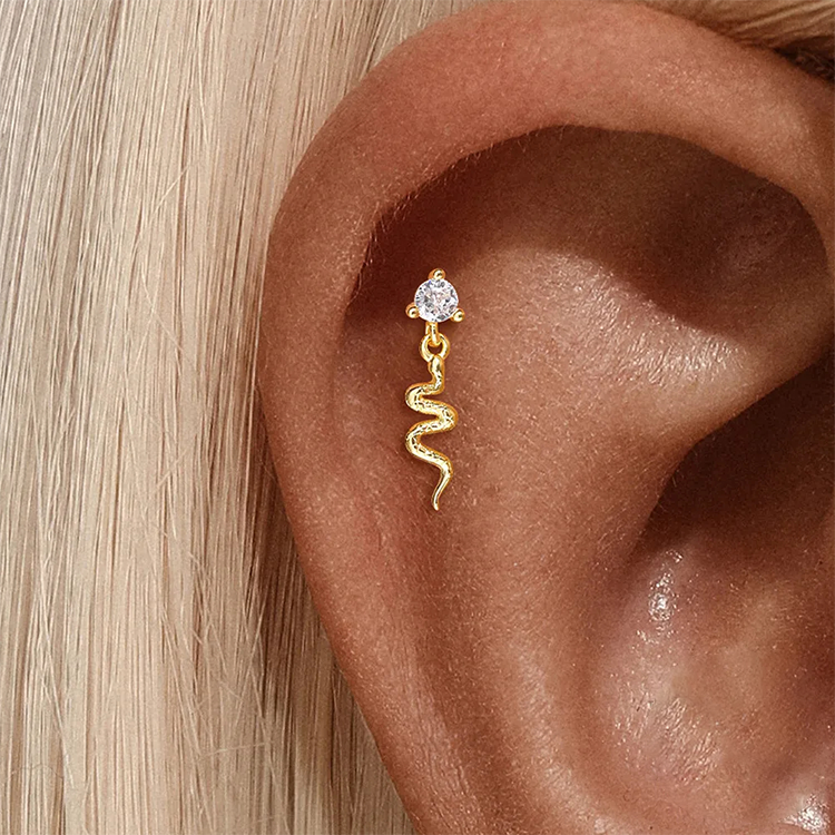 Gold snake-shaped earring with a diamond on an ear