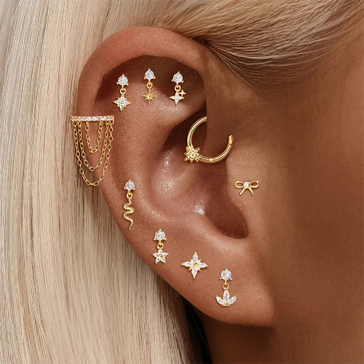 Close-up of an ear with multiple gold earrings and a gold hoop earring.