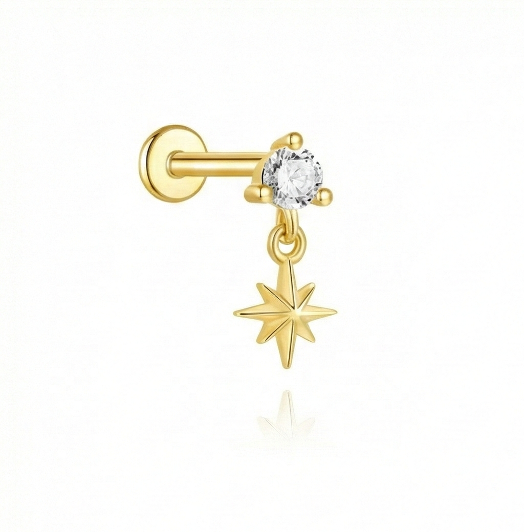 Gold nose ring with a star-shaped charm and clear gemstone on a white background