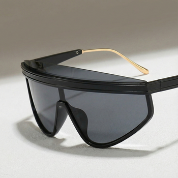 Black sunglasses with gold accents on a light gray background