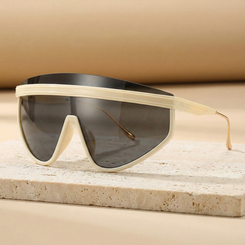 Sunglasses with beige frame and dark lenses on a light stone surface