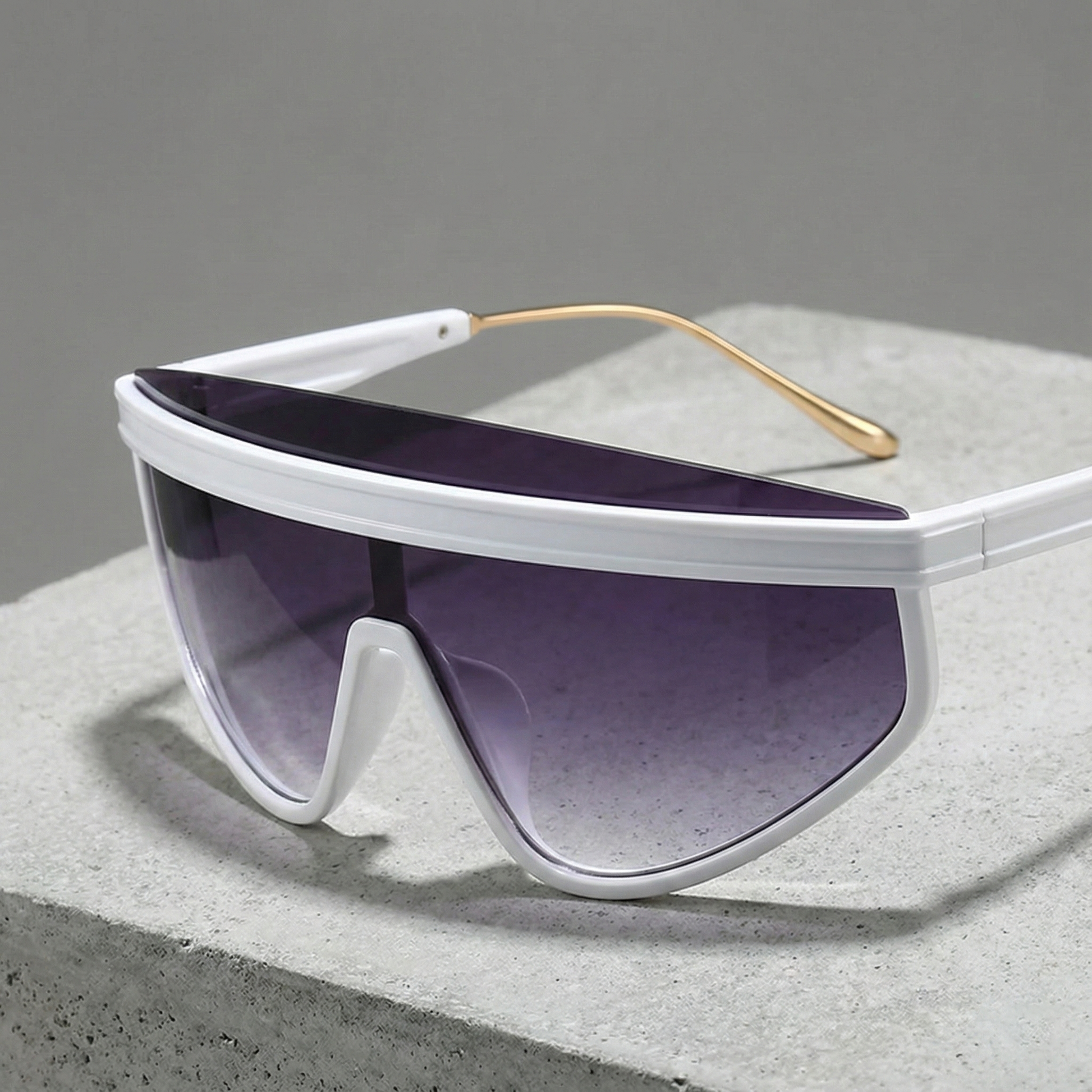 White sunglasses with gold accents on a gray surface