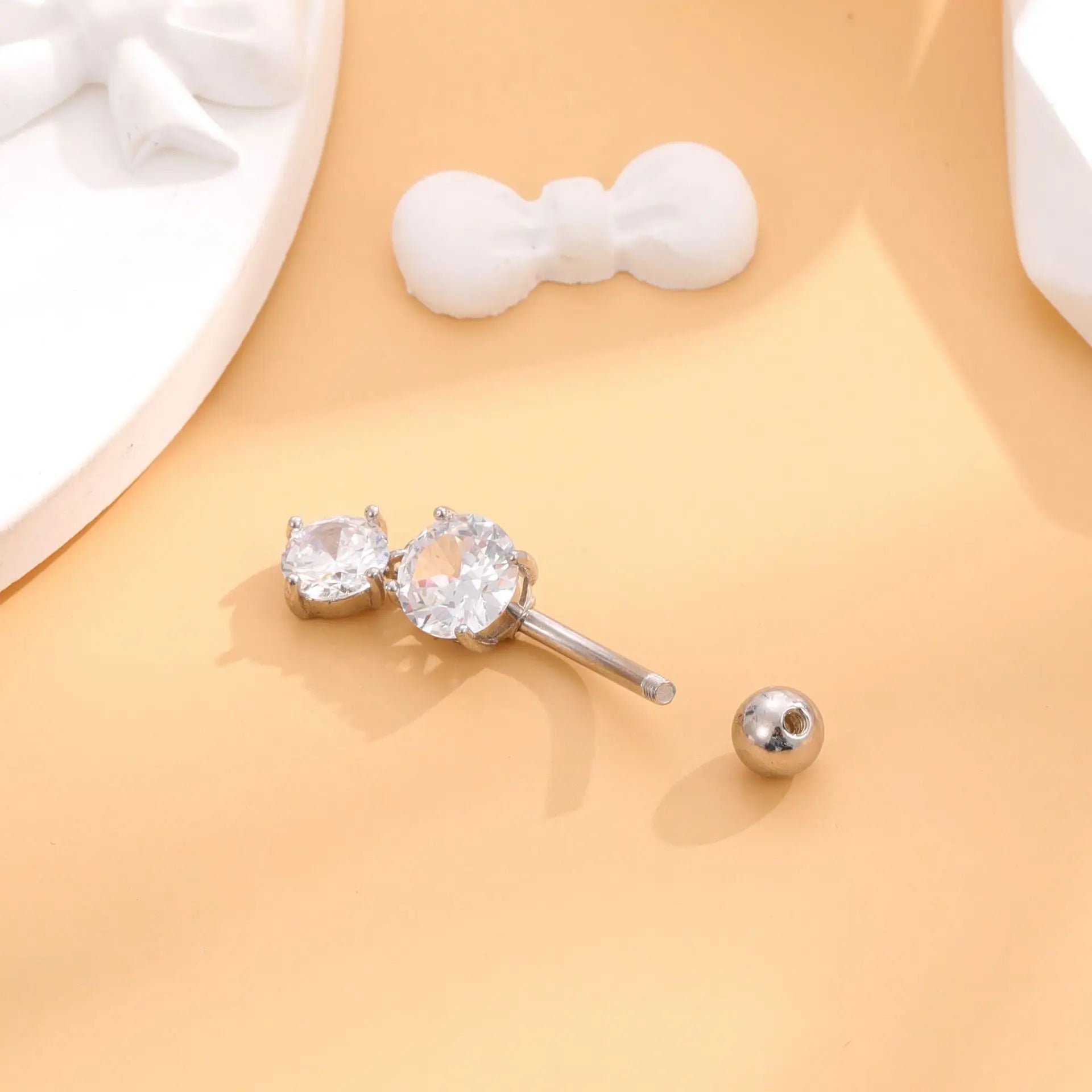 Silver earring with clear gemstone on a beige surface