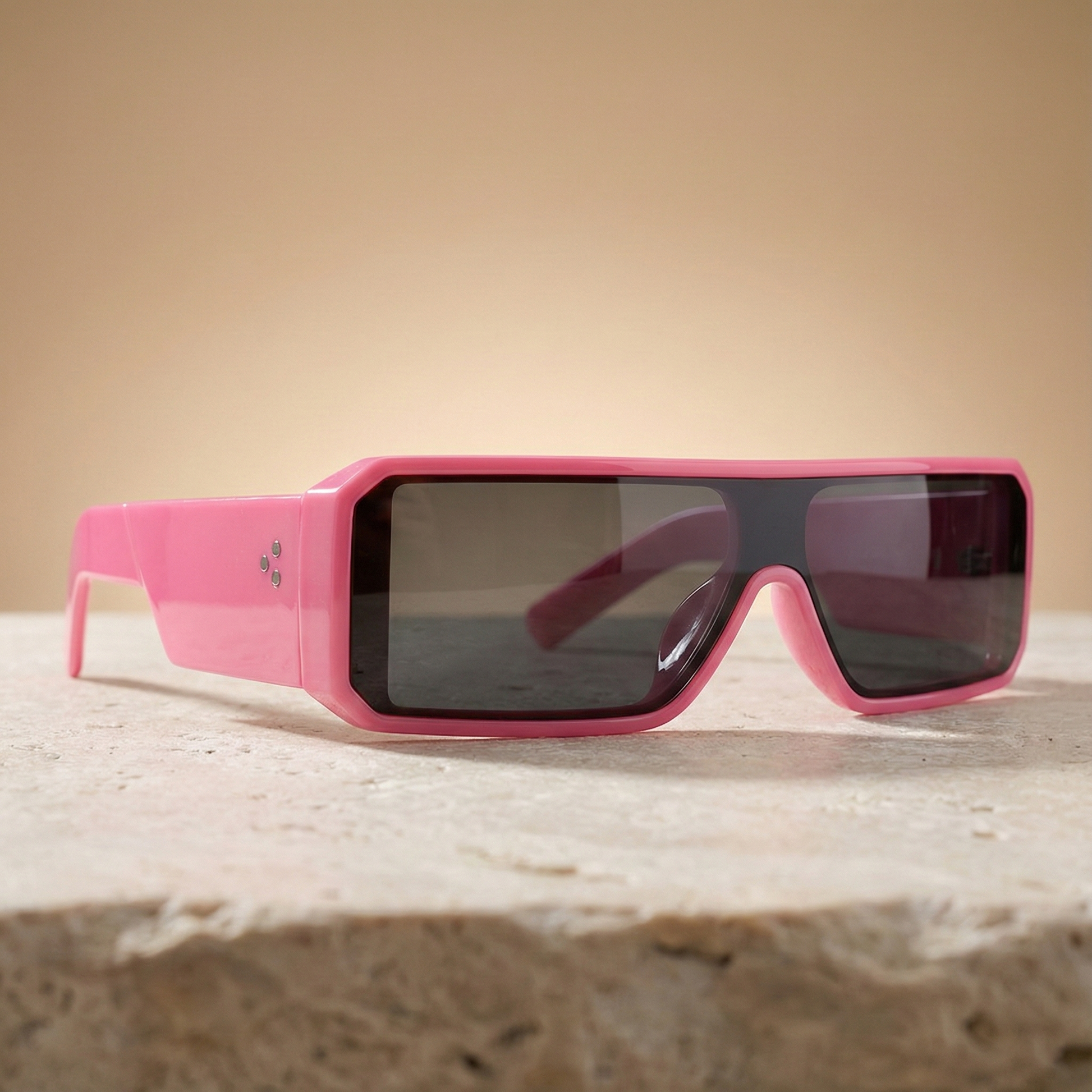 Pink sunglasses with black lenses on a beige surface