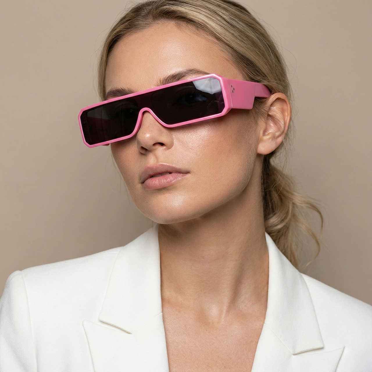 Woman wearing pink sunglasses and a white blazer against a beige background