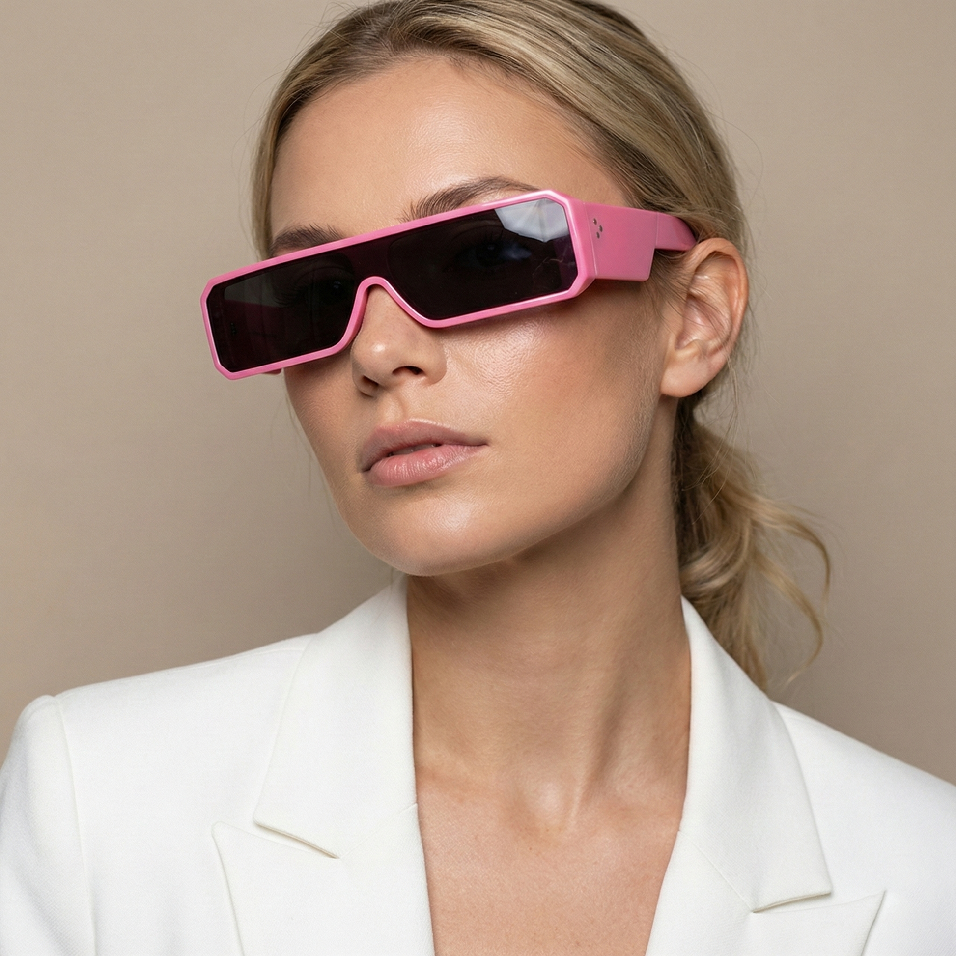 Woman wearing pink sunglasses and a white blazer against a beige background