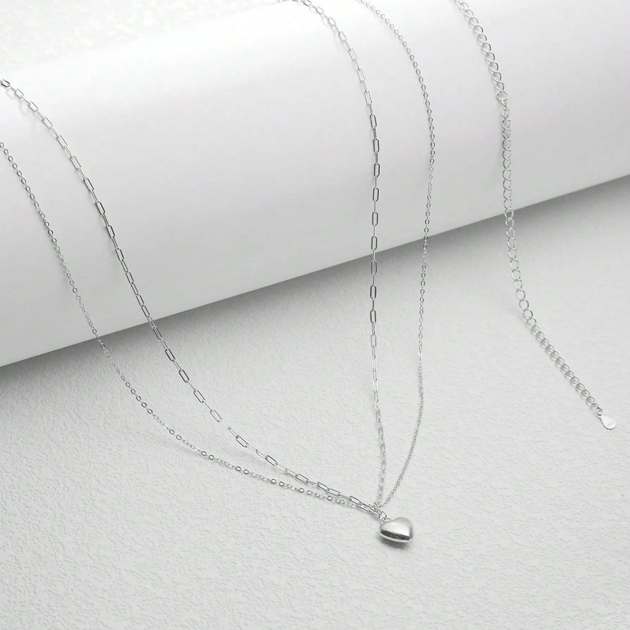 Close-up of a person wearing a delicate chain belt with a heart pendant.