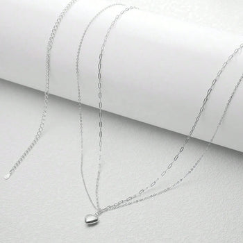 Silver chain necklaces on a light gray surface
