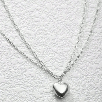 Silver heart-shaped pendant necklace on a textured white background