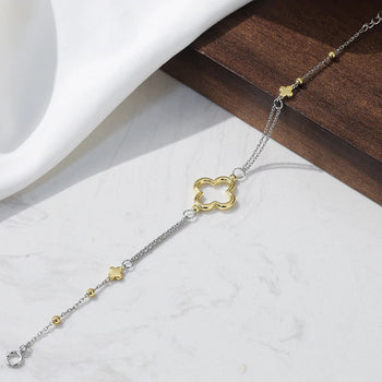 Gold and silver bracelet with clover-shaped clasp on a white surface