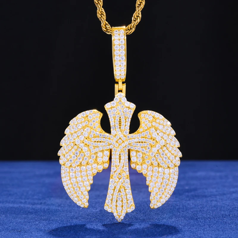 Gold pendant with wings and cross design on a blue fabric background