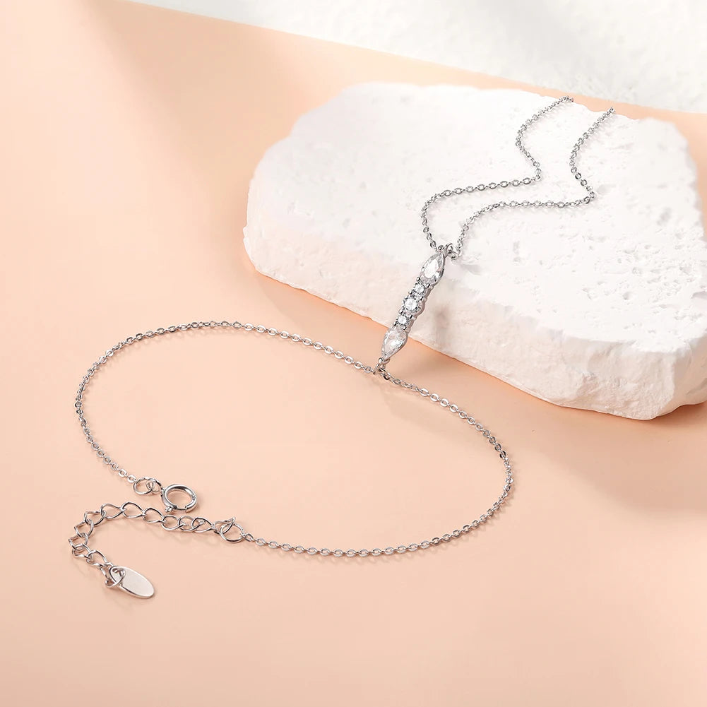 Silver necklace with a clear gemstone on a beige surface