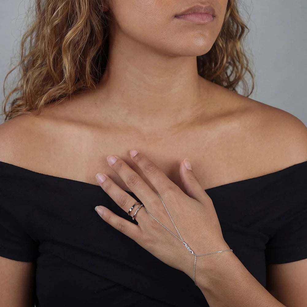 Silver necklace with a clear gemstone on a beige surface