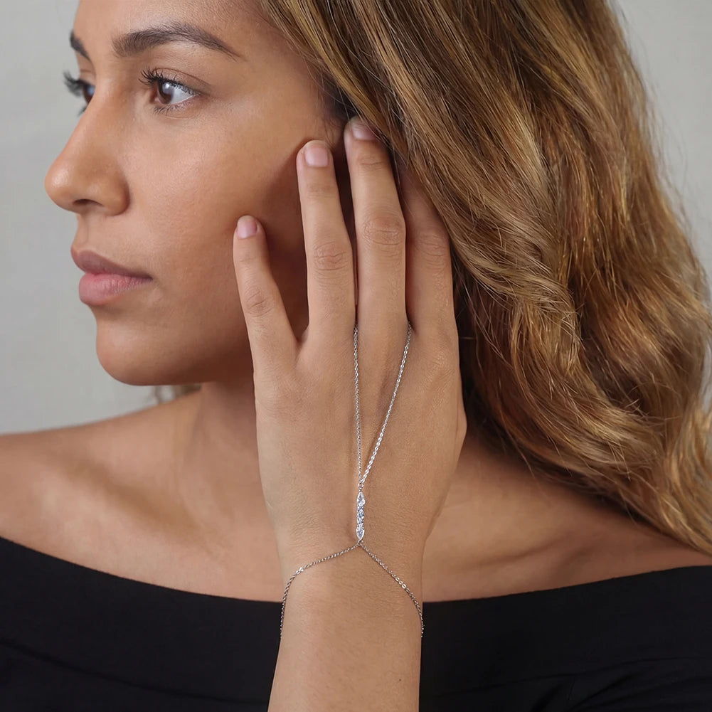 Woman wearing a delicate silver bracelet with a clear gemstone on a neutral background