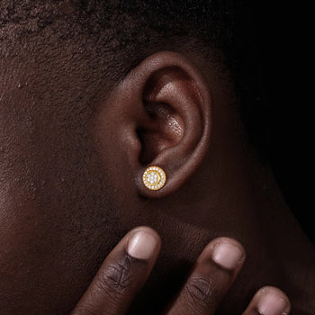 Close-up of an ear wearing a gold earring with a hand touching the earlobe.