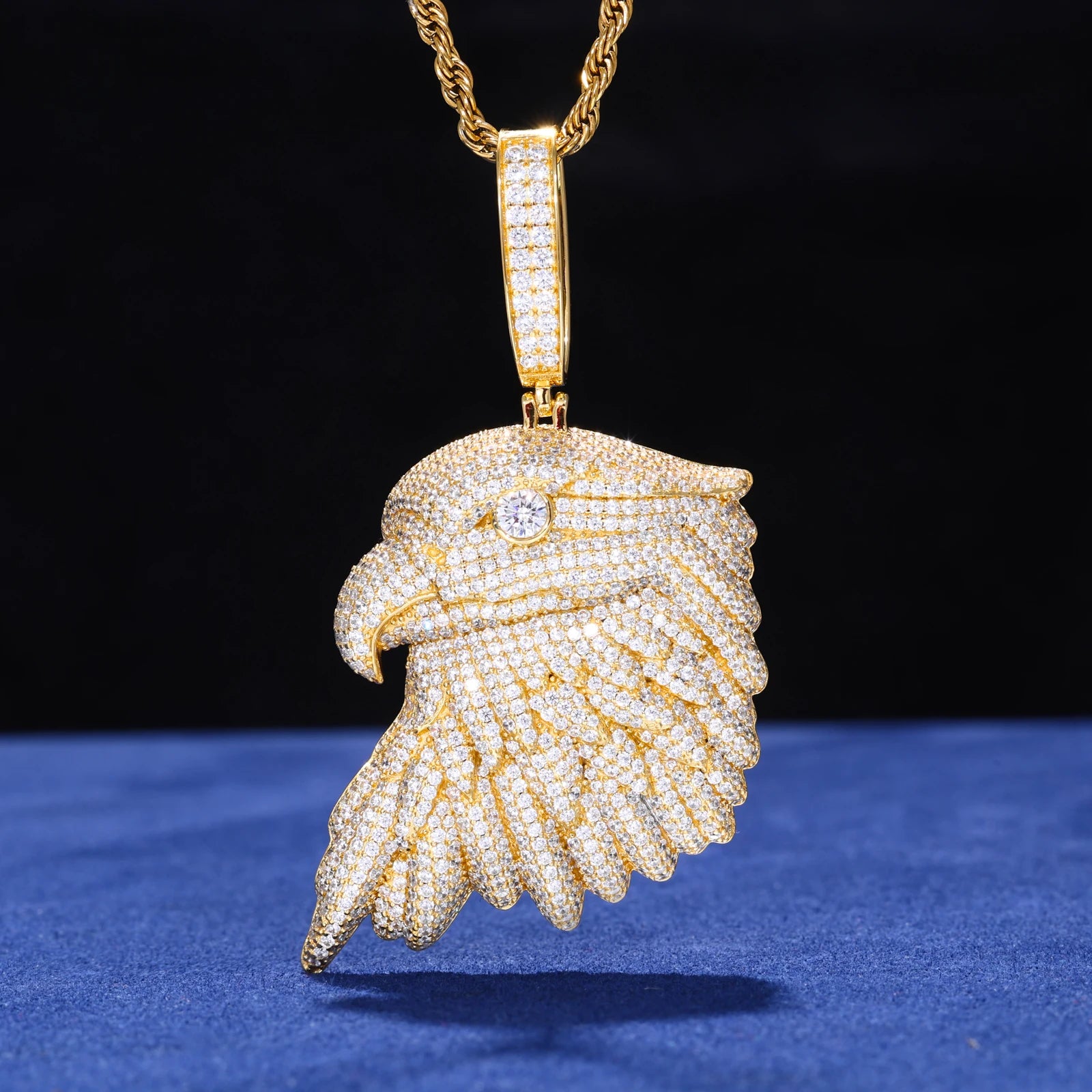 Gold eagle pendant necklace on a blue surface with a black background