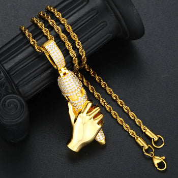 Gold hand-shaped pendant with chain on a dark background