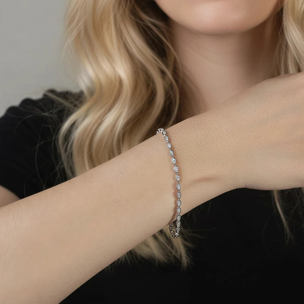 Close-up of a person wearing a delicate bracelet with small stones on a neutral background