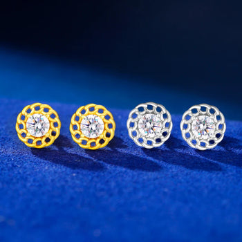 Two pairs of gold and silver stud earrings on a blue fabric background