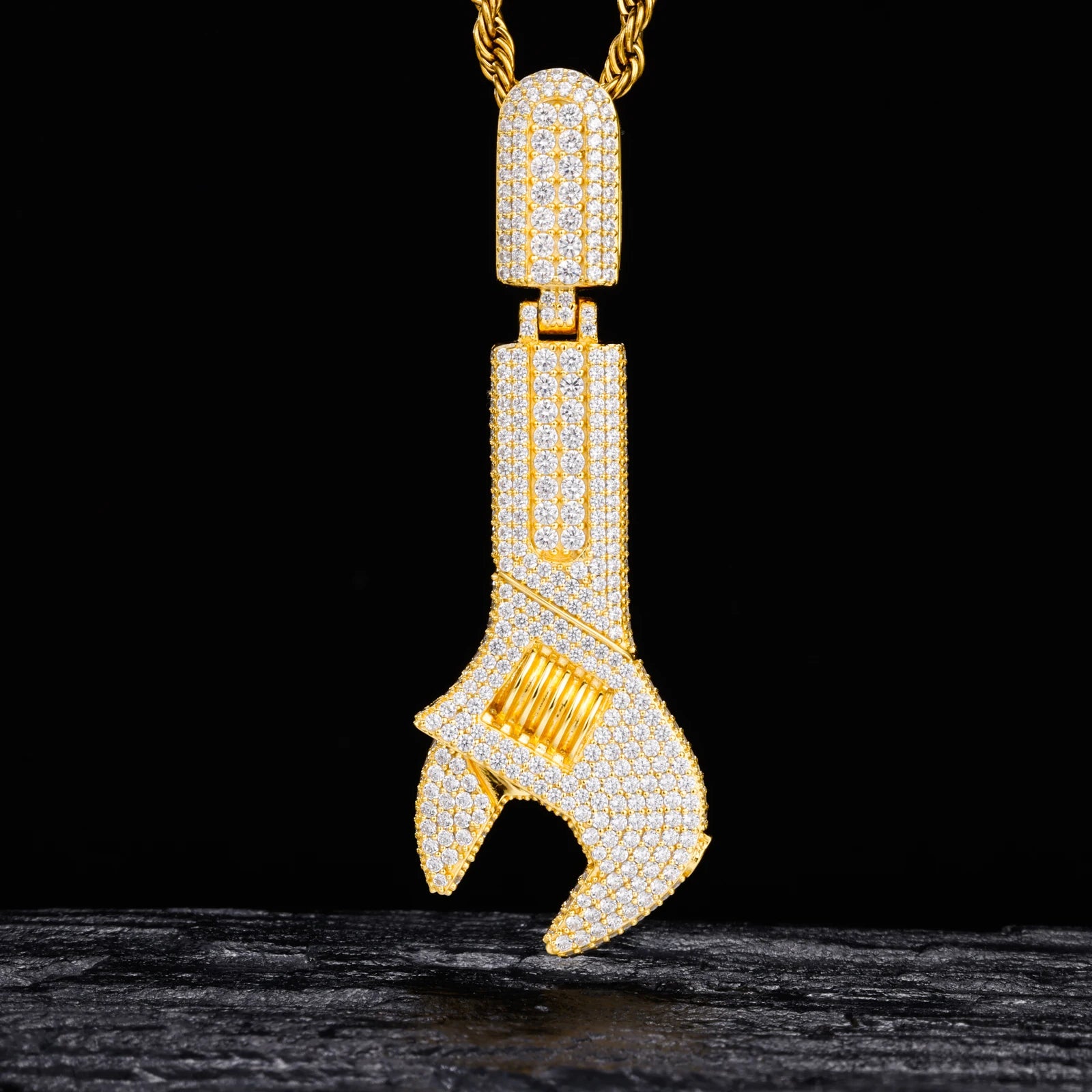 Gold wrench-shaped pendant with diamonds on a black background