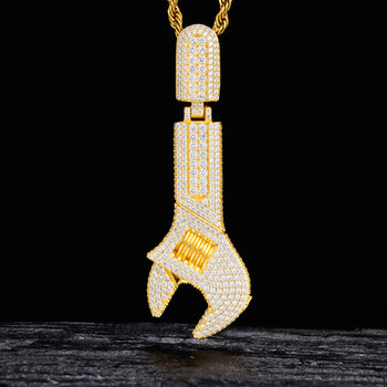 Gold wrench-shaped pendant with diamonds on a black background