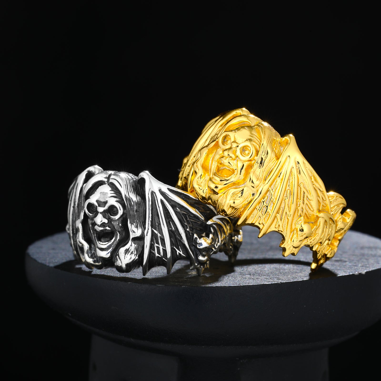 Gold and silver bat-shaped rings on a black background