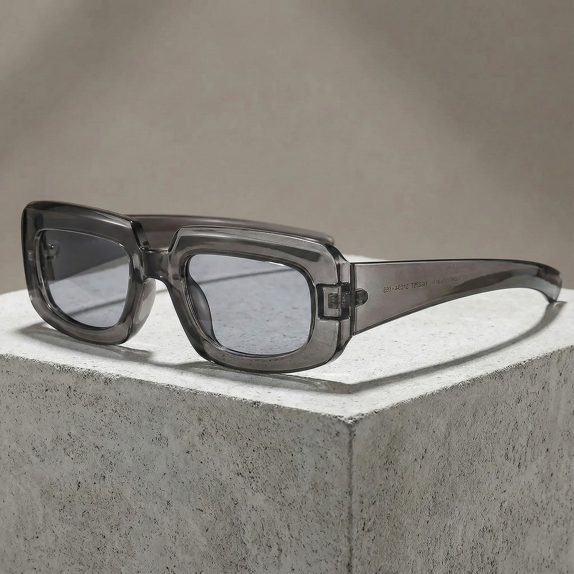 Sunglasses with a transparent frame and dark lenses on a concrete surface.