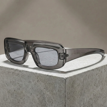Sunglasses with a transparent frame and dark lenses on a concrete surface.