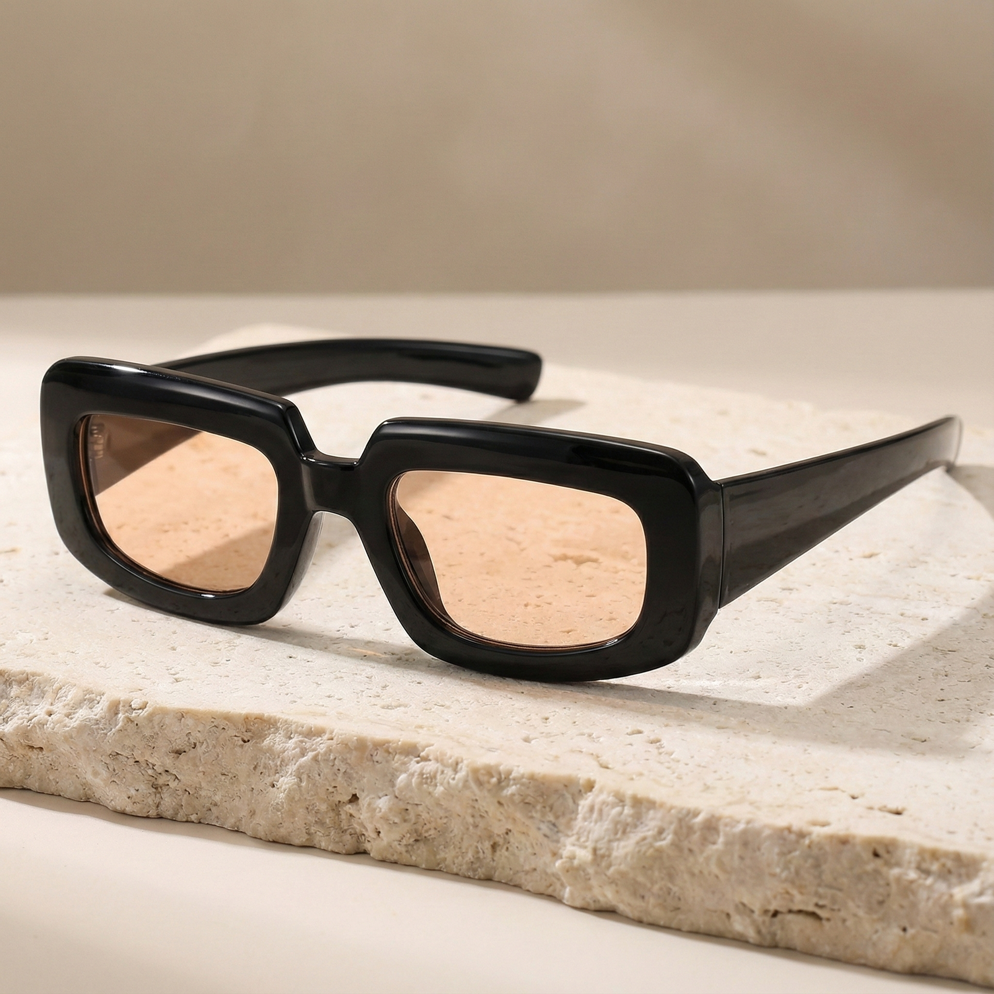 Black sunglasses with beige lenses on a light stone surface
