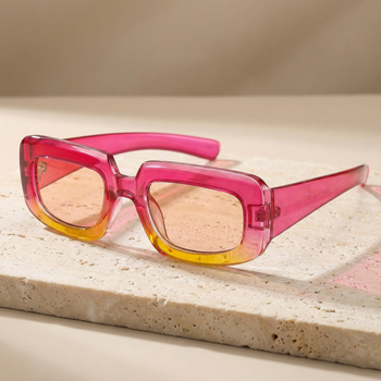 Sunglasses with pink and orange gradient lenses on a stone surface