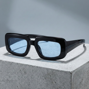 Black sunglasses with blue lenses on a concrete surface
