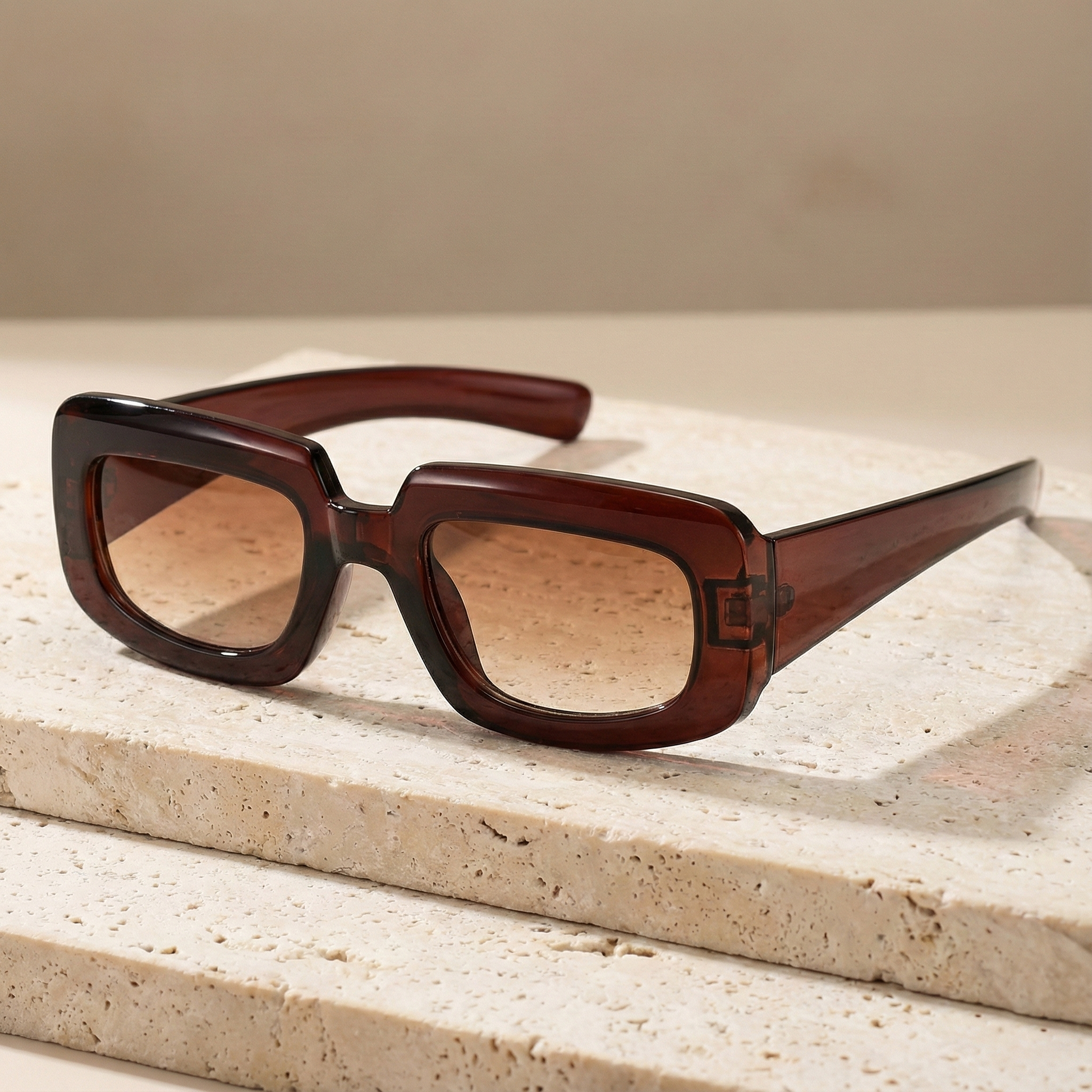 Brown sunglasses on a textured beige surface