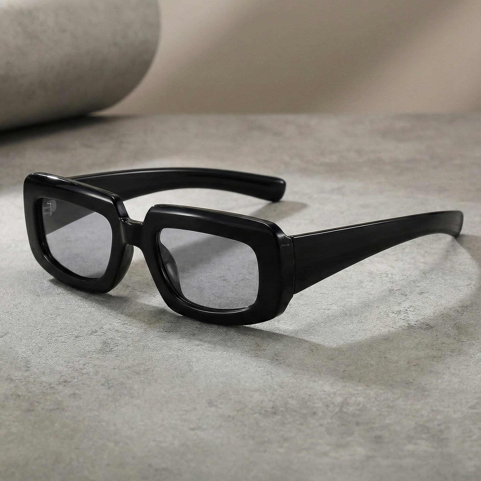 Black rectangular sunglasses on a gray surface