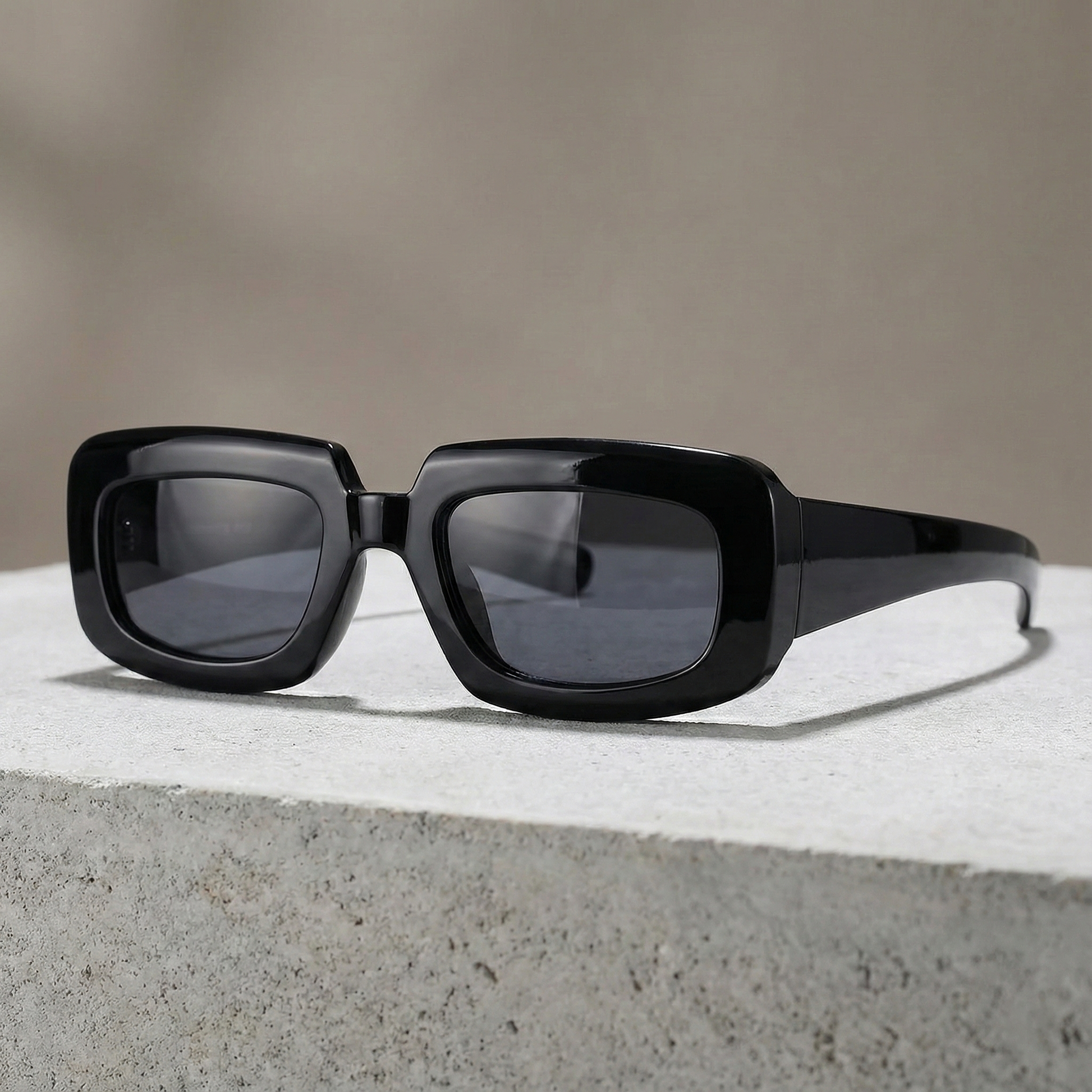 Black sunglasses with dark lenses on a concrete surface with a neutral background